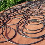 The 200 m of black 16 mm irrigation pipe coiled on the bitumen roof of the tool shack, 2018