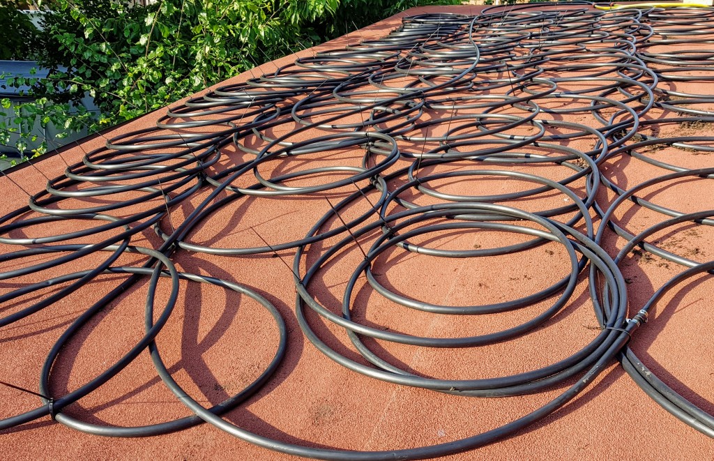 The 200 m of black 16 mm irrigation pipe coiled on the bitumen roof of the tool shack, 2018